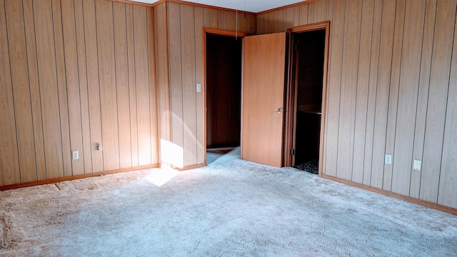 unfurnished bedroom with carpet flooring and wood walls