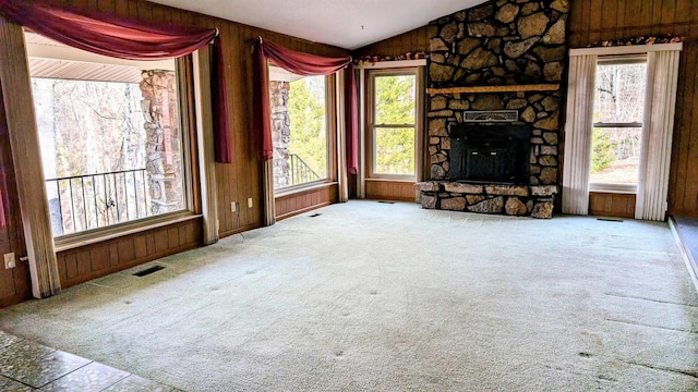 living room featuring carpet, lofted ceiling, wood walls, and a fireplace