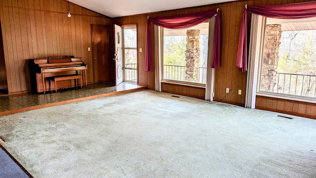 interior space with wood walls, a wealth of natural light, and lofted ceiling