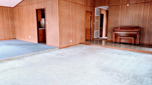 unfurnished living room with lofted ceiling, carpet flooring, and wood walls