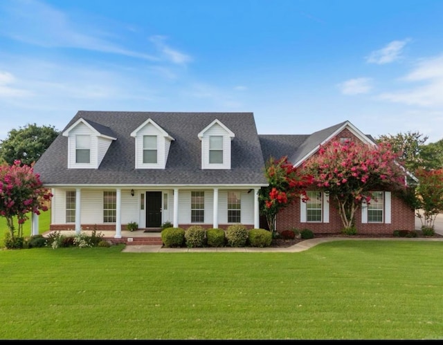 cape cod home featuring covered porch and a front lawn