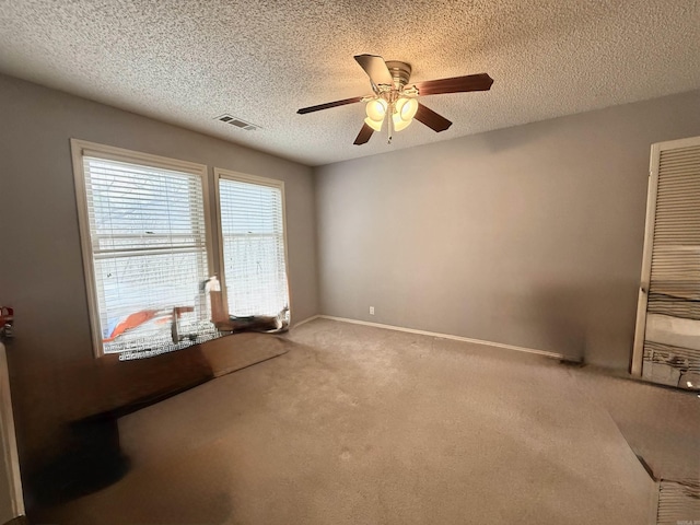 carpeted spare room featuring ceiling fan and a textured ceiling