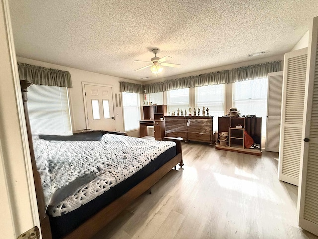 bedroom with multiple windows, ceiling fan, a textured ceiling, and light wood-type flooring