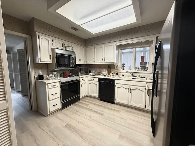 kitchen with white cabinets, appliances with stainless steel finishes, sink, and light wood-type flooring