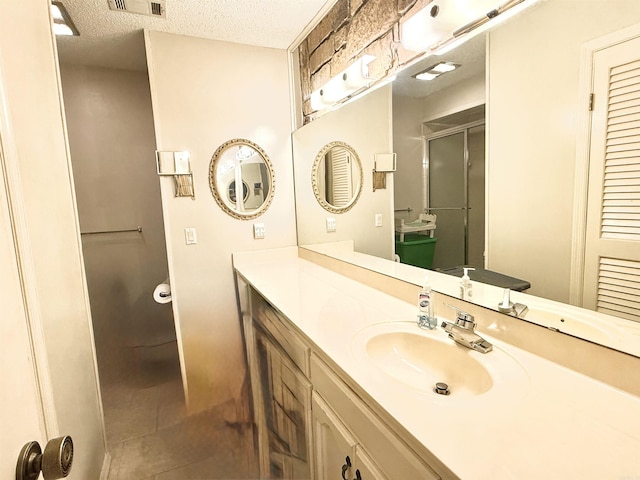 bathroom with walk in shower, vanity, and a textured ceiling