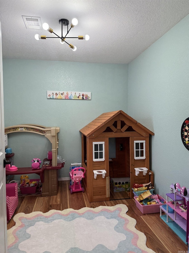 bedroom with an inviting chandelier, dark hardwood / wood-style flooring, and a textured ceiling