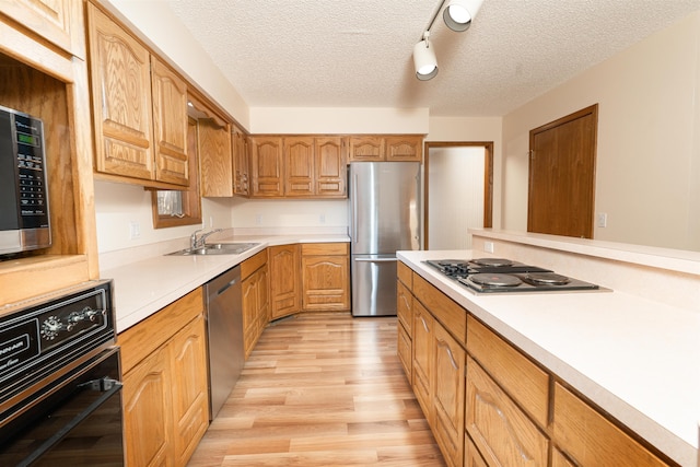 kitchen with sink, light hardwood / wood-style flooring, a textured ceiling, and appliances with stainless steel finishes