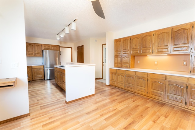 kitchen featuring a textured ceiling, stainless steel fridge, and light hardwood / wood-style floors