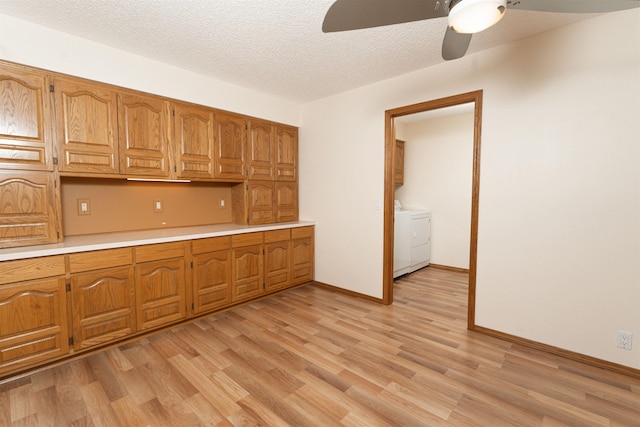 kitchen featuring ceiling fan, independent washer and dryer, light hardwood / wood-style flooring, and a textured ceiling