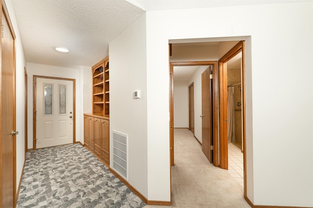 hallway featuring light carpet and a textured ceiling