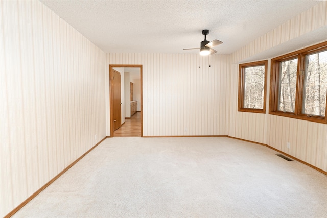 unfurnished room featuring ceiling fan, light colored carpet, and a textured ceiling