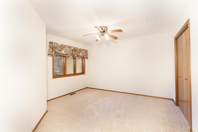 carpeted empty room with a textured ceiling and ceiling fan