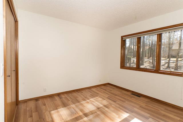 spare room featuring a textured ceiling and light wood-type flooring