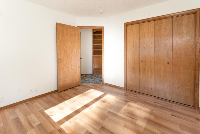 unfurnished bedroom with a closet, light hardwood / wood-style floors, and a textured ceiling