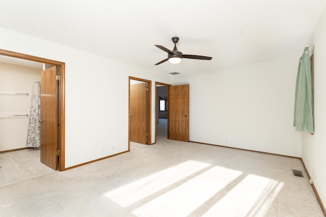 unfurnished bedroom featuring ceiling fan, light carpet, and a textured ceiling