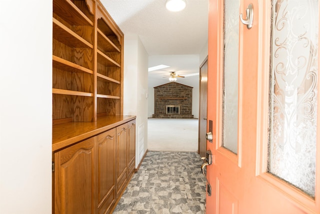 corridor with lofted ceiling, carpet flooring, and a textured ceiling