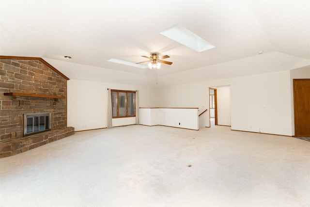 unfurnished living room with light carpet, a fireplace, lofted ceiling with skylight, and ceiling fan