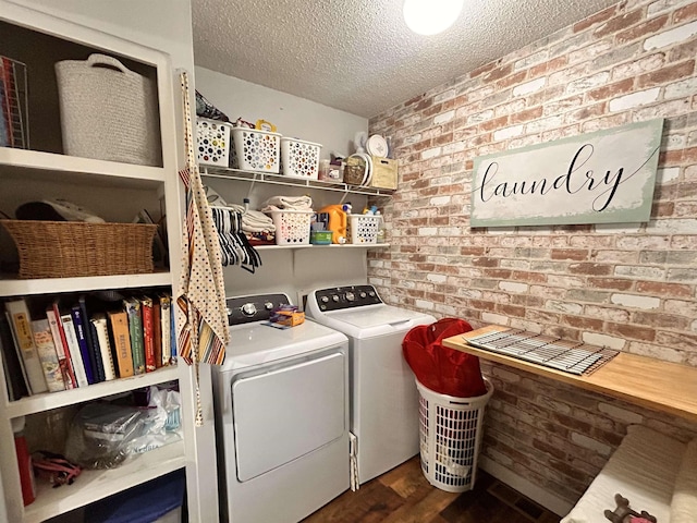 clothes washing area with brick wall, dark hardwood / wood-style floors, a textured ceiling, and independent washer and dryer