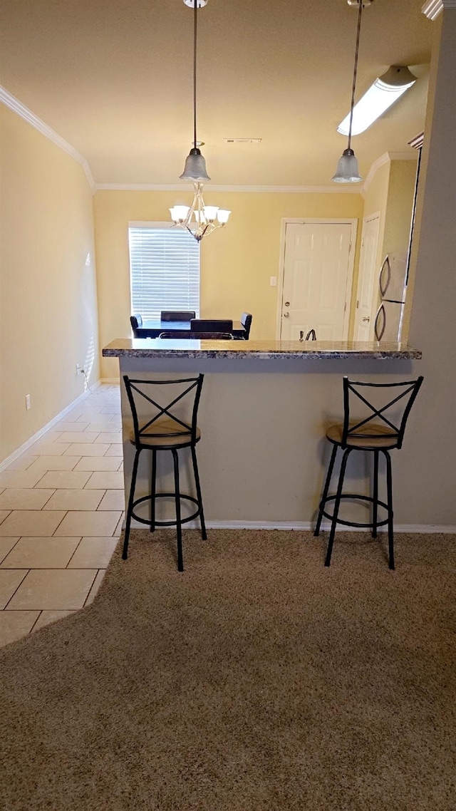 kitchen with ornamental molding, a breakfast bar, kitchen peninsula, and decorative light fixtures