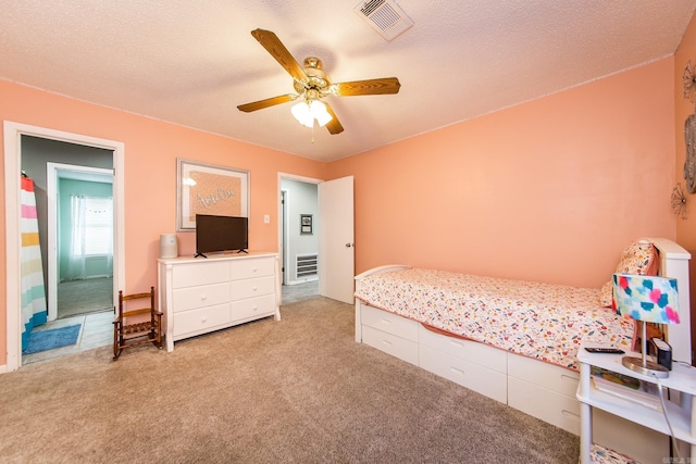 carpeted bedroom featuring ceiling fan and a textured ceiling