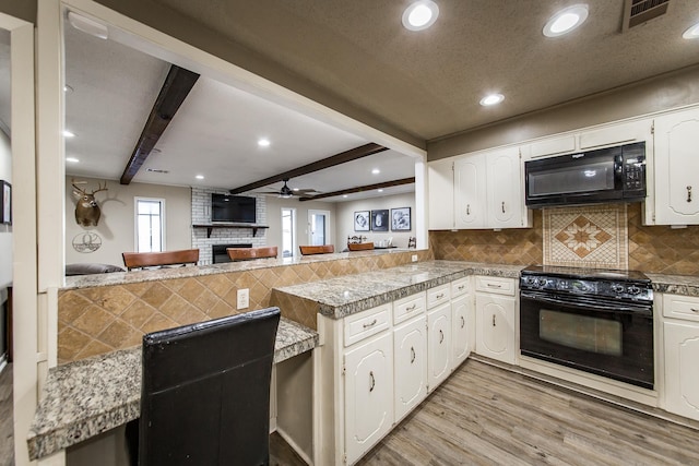 kitchen with beamed ceiling, white cabinets, kitchen peninsula, and black appliances