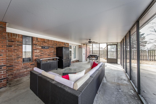 interior space featuring ceiling fan, brick wall, and concrete floors