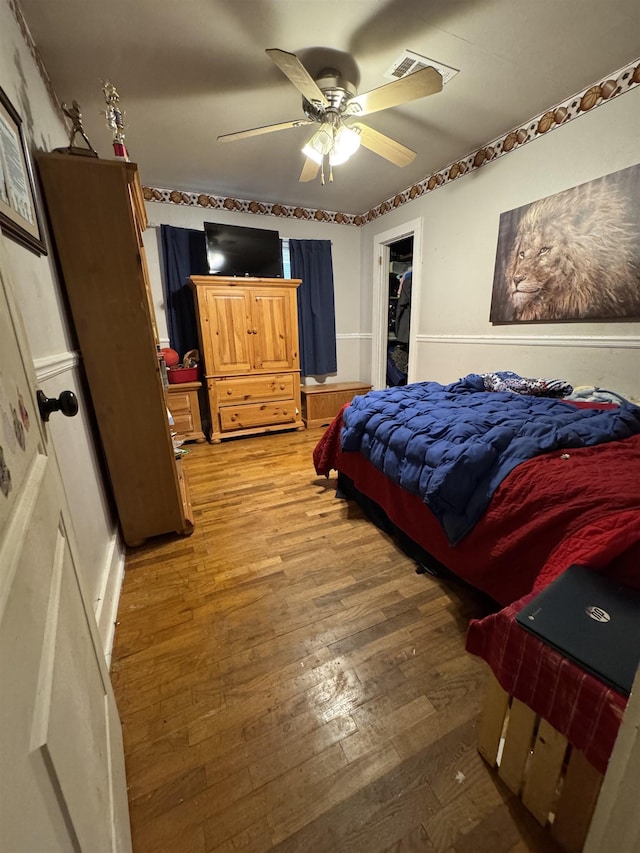 bedroom with wood-type flooring, a spacious closet, and ceiling fan