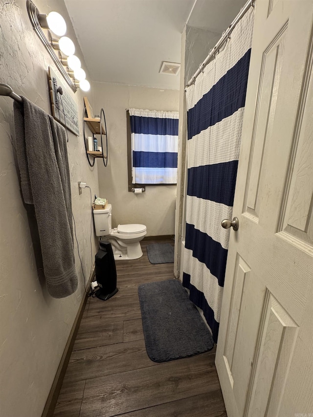 bathroom featuring walk in shower, wood-type flooring, and toilet