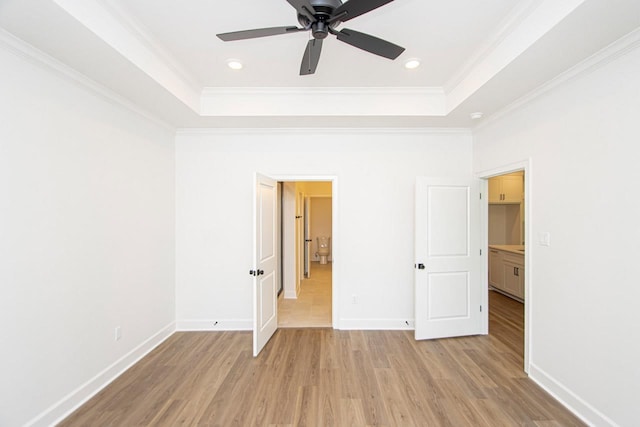 unfurnished bedroom featuring ornamental molding, a raised ceiling, and light wood-type flooring