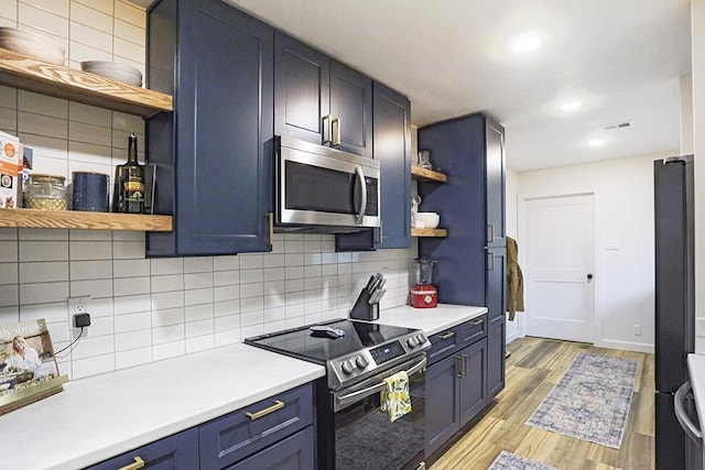 kitchen with blue cabinets, appliances with stainless steel finishes, backsplash, and light hardwood / wood-style flooring