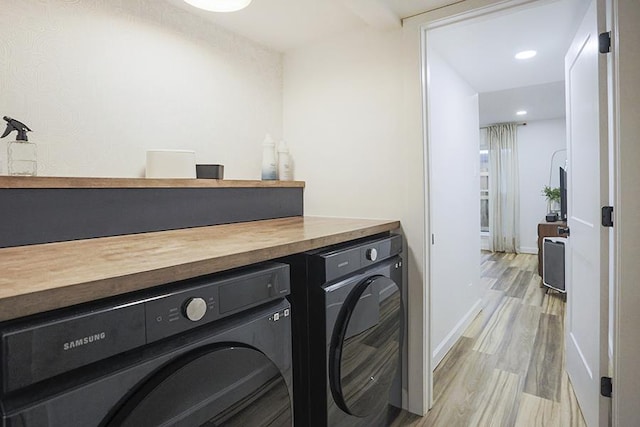 laundry area with washer and dryer and light hardwood / wood-style flooring
