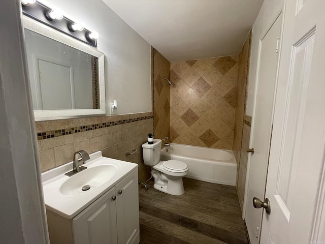 full bathroom with tiled shower / bath, hardwood / wood-style floors, tile walls, vanity, and toilet