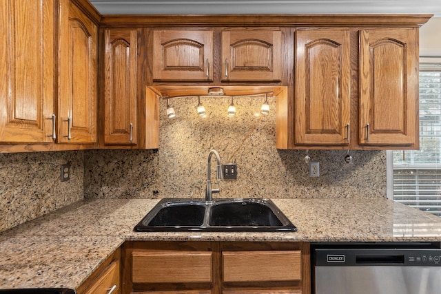 kitchen with light stone countertops, sink, stainless steel dishwasher, and backsplash