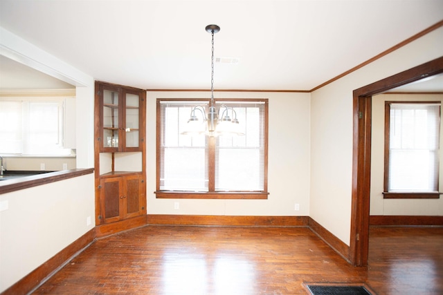 unfurnished dining area with ornamental molding, dark wood-type flooring, and a chandelier