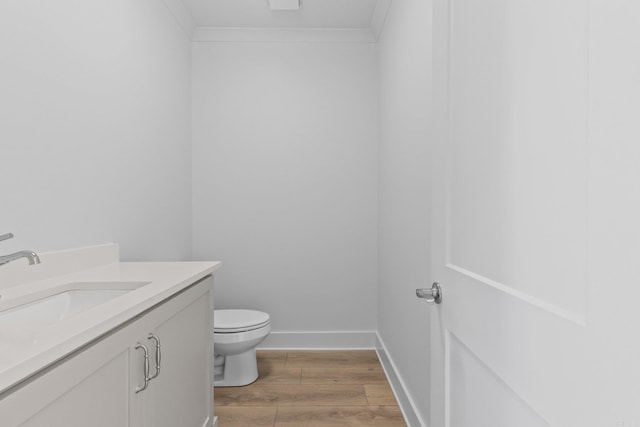 bathroom featuring vanity, wood finished floors, toilet, and crown molding