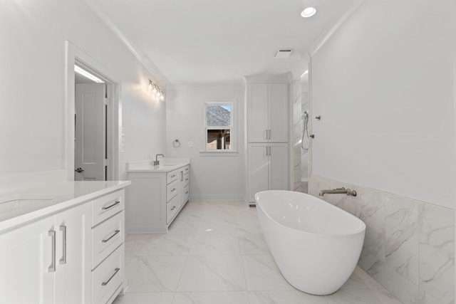 bathroom featuring marble finish floor, a freestanding bath, ornamental molding, and a sink