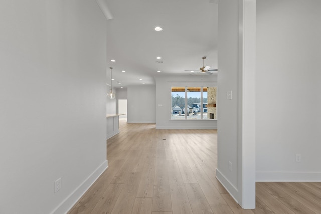 corridor with light wood-style flooring, baseboards, and recessed lighting