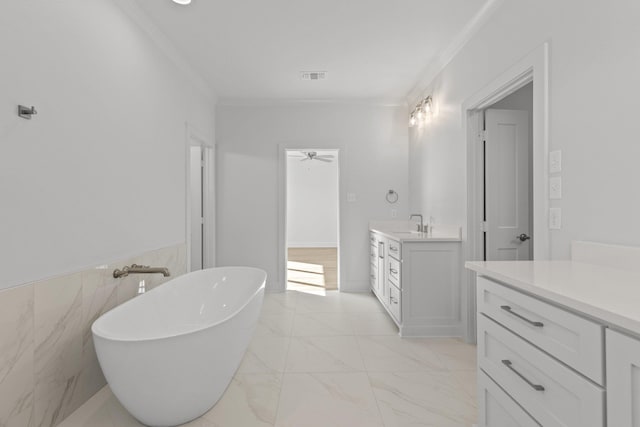 bathroom with marble finish floor, visible vents, a freestanding bath, ornamental molding, and vanity