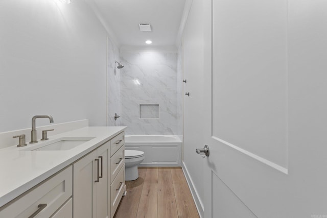 bathroom with toilet, vanity, shower / tub combination, wood finished floors, and baseboards