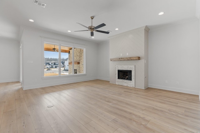 unfurnished living room featuring light wood-style flooring, a fireplace, visible vents, and a ceiling fan