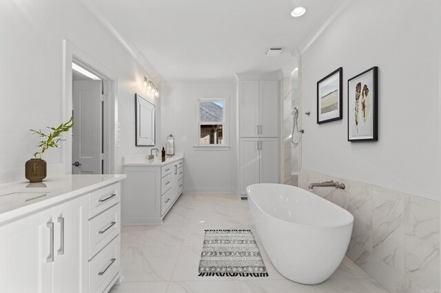 full bath featuring a sink, two vanities, a freestanding bath, marble finish floor, and ornamental molding