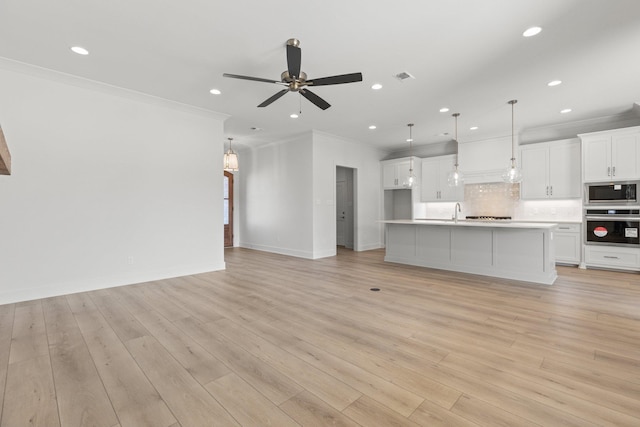 unfurnished living room with light wood finished floors, recessed lighting, ornamental molding, ceiling fan, and baseboards