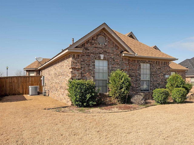 view of side of property featuring cooling unit and a yard