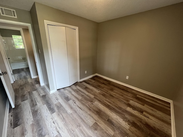 unfurnished bedroom with hardwood / wood-style floors, a textured ceiling, and a closet