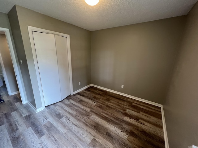 unfurnished bedroom with hardwood / wood-style flooring, a closet, and a textured ceiling