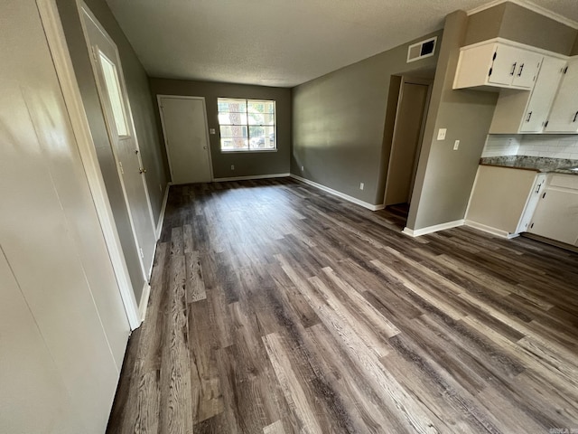 unfurnished living room with dark wood-type flooring and a textured ceiling