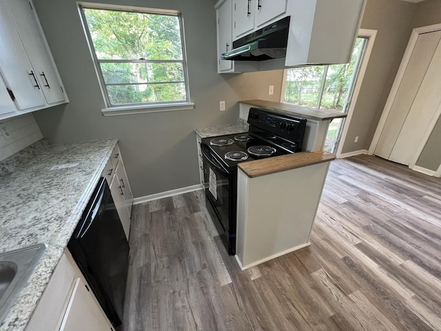 kitchen featuring white cabinetry, light stone counters, hardwood / wood-style flooring, and black appliances