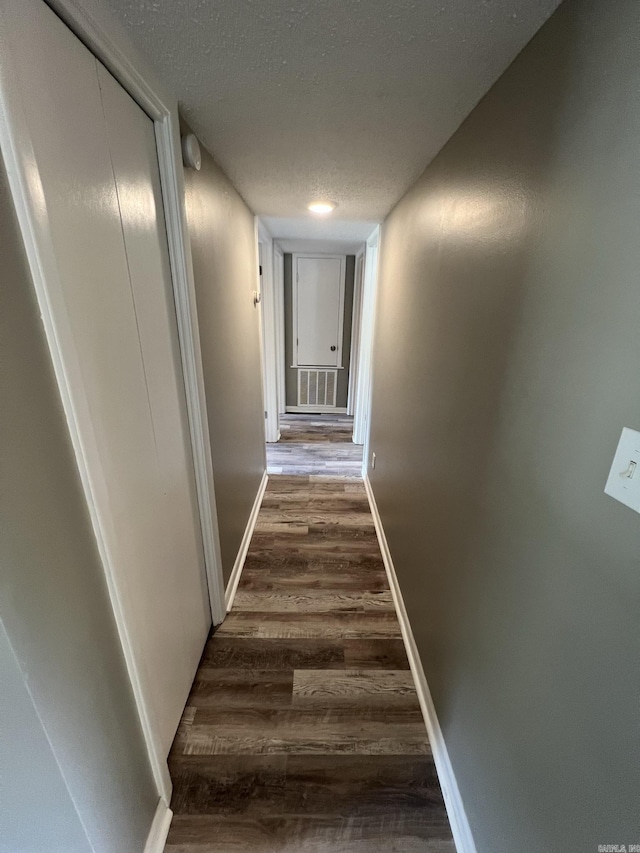 hall featuring dark hardwood / wood-style floors and a textured ceiling