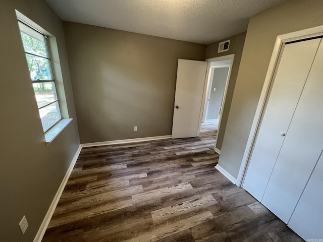 unfurnished bedroom with a textured ceiling and dark hardwood / wood-style flooring