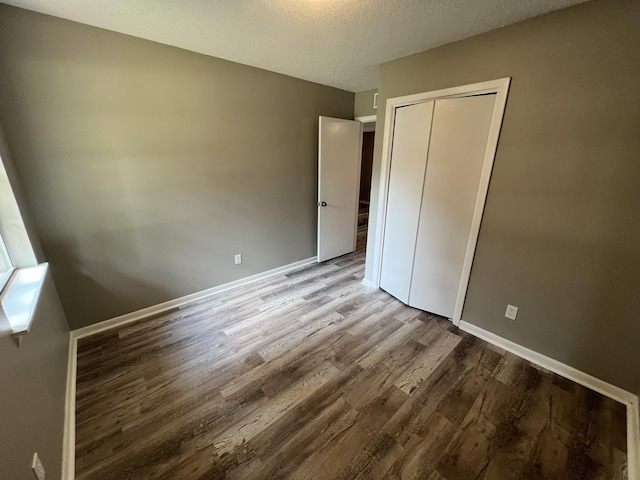 unfurnished bedroom featuring wood-type flooring, a textured ceiling, and a closet